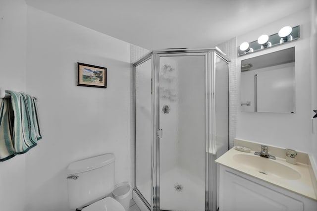 bathroom featuring a shower with door, vanity, and toilet