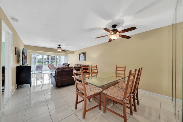 tiled dining space with a textured ceiling and ceiling fan