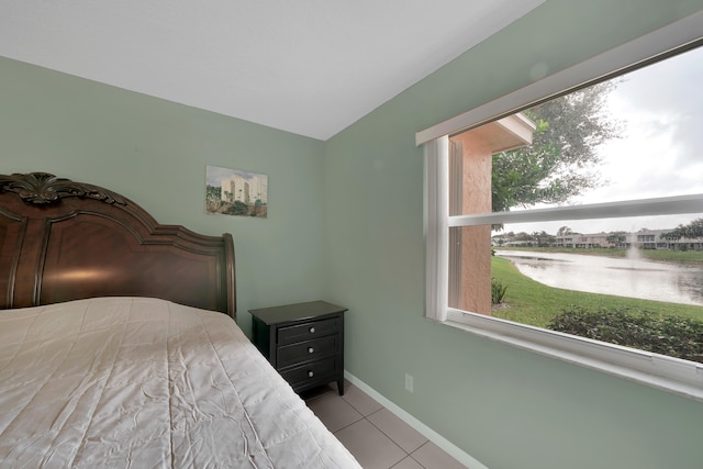 bedroom with a water view, multiple windows, and light tile patterned flooring