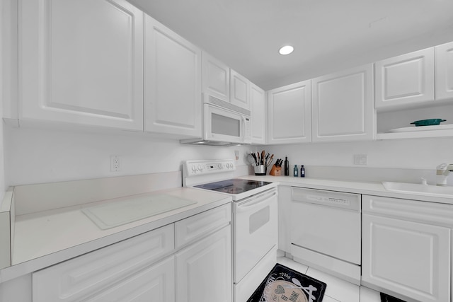 kitchen featuring white appliances, white cabinetry, sink, and light tile patterned flooring