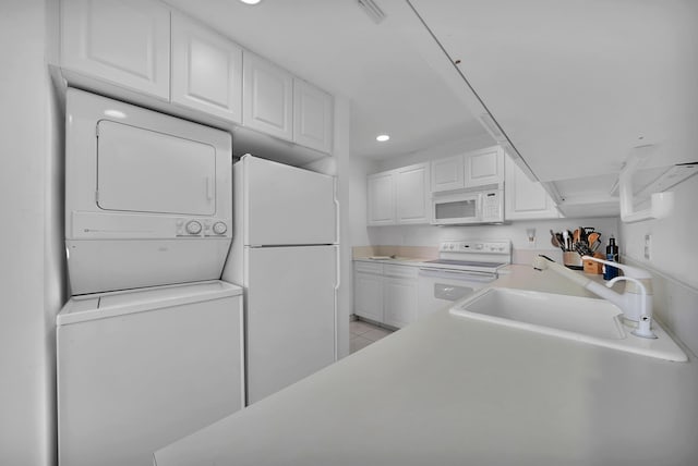 kitchen featuring white cabinetry, sink, light tile patterned floors, white appliances, and stacked washing maching and dryer