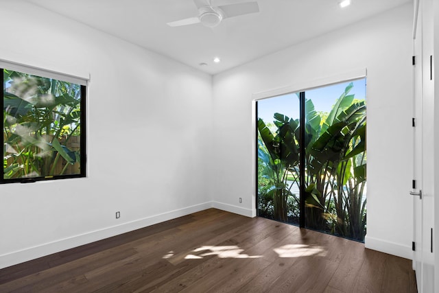 empty room with dark hardwood / wood-style floors, a wealth of natural light, and ceiling fan