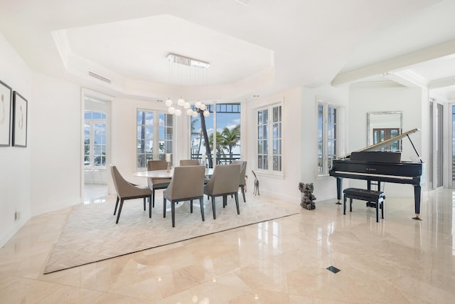 dining room featuring a raised ceiling, a healthy amount of sunlight, and a chandelier