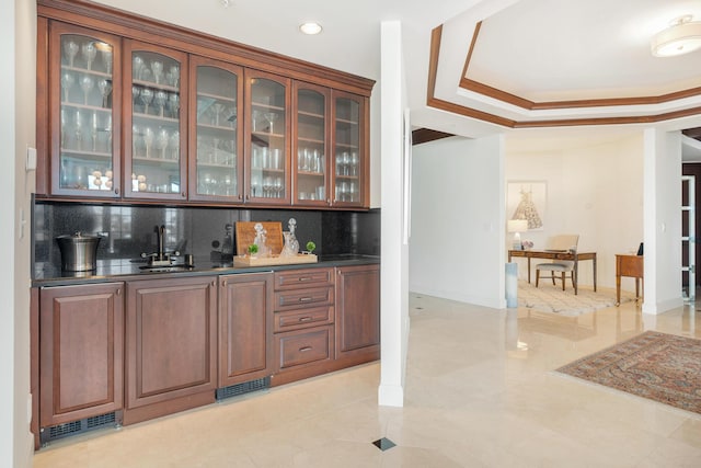 bar featuring sink, crown molding, backsplash, and a tray ceiling