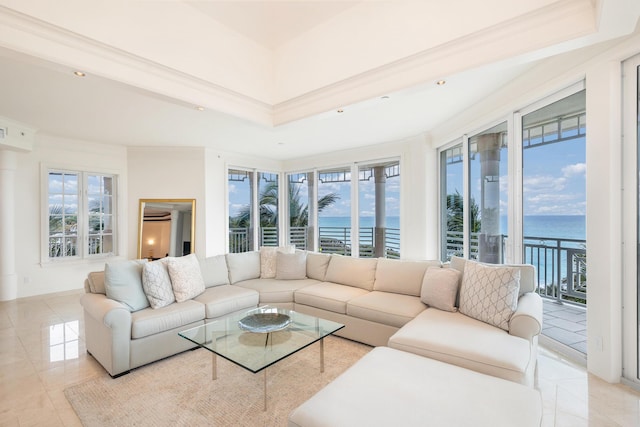 tiled living room with a water view, crown molding, a wealth of natural light, and a tray ceiling