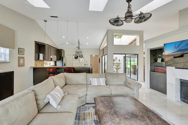 living room with a skylight, high vaulted ceiling, and ceiling fan