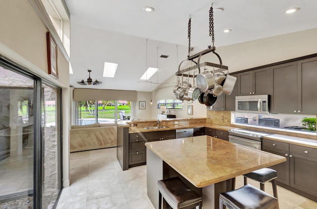 kitchen with a breakfast bar, lofted ceiling with skylight, backsplash, sink, and light stone countertops