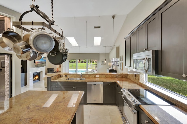 kitchen featuring appliances with stainless steel finishes, sink, decorative light fixtures, lofted ceiling, and light tile patterned flooring