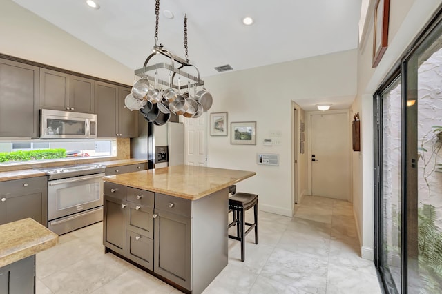 kitchen with decorative backsplash, appliances with stainless steel finishes, light stone countertops, a kitchen breakfast bar, and a center island