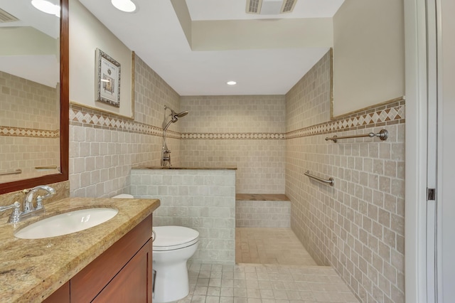 bathroom featuring a tile shower, vanity, tile patterned floors, and tile walls