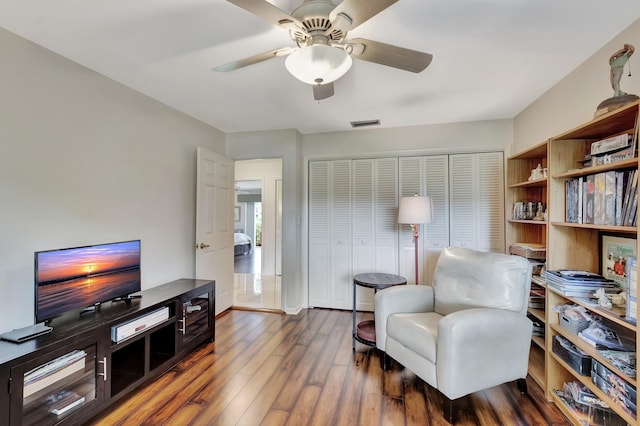 living area with dark hardwood / wood-style flooring and ceiling fan