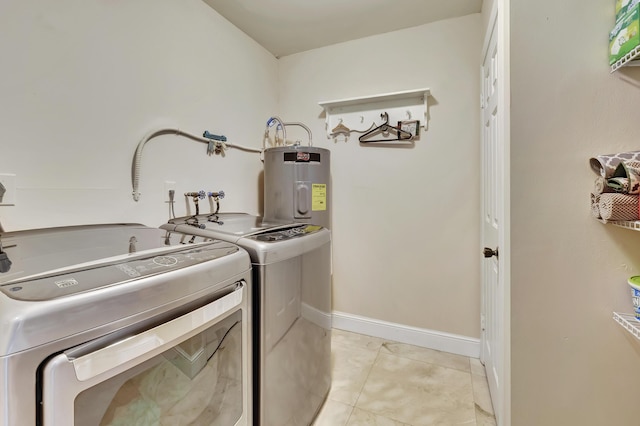 clothes washing area with light tile patterned floors, washer and clothes dryer, and water heater