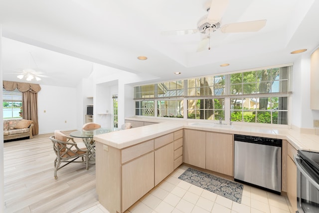 kitchen featuring light brown cabinetry, tile counters, ceiling fan, kitchen peninsula, and stainless steel appliances