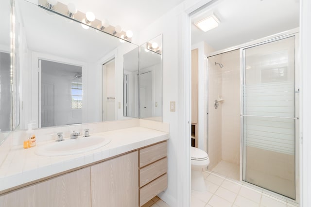 bathroom with a shower with door, vanity, tile patterned floors, and toilet