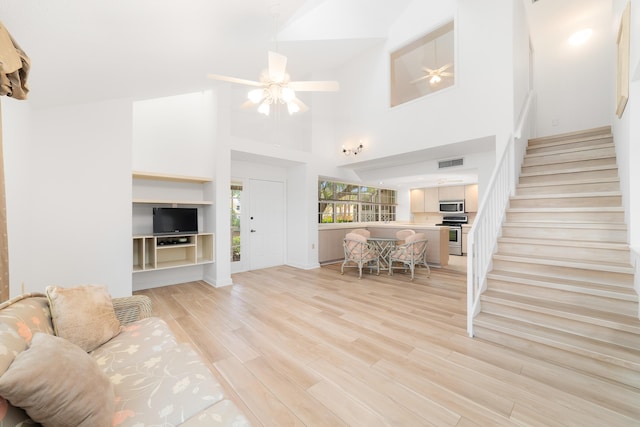 living room featuring ceiling fan, high vaulted ceiling, and light hardwood / wood-style flooring