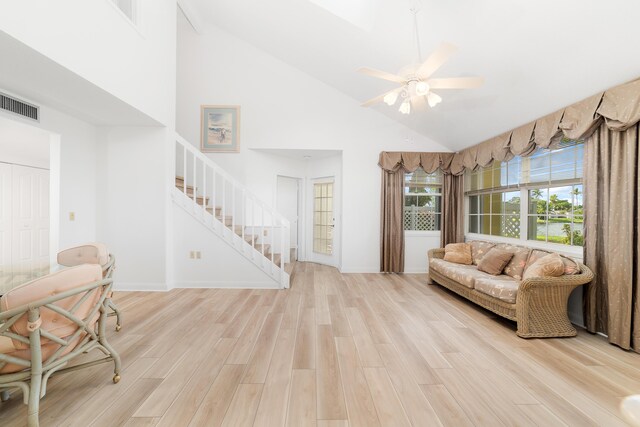 living room with ceiling fan, light hardwood / wood-style floors, and high vaulted ceiling