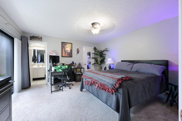 carpeted bedroom featuring ceiling fan, a textured ceiling, and ensuite bath