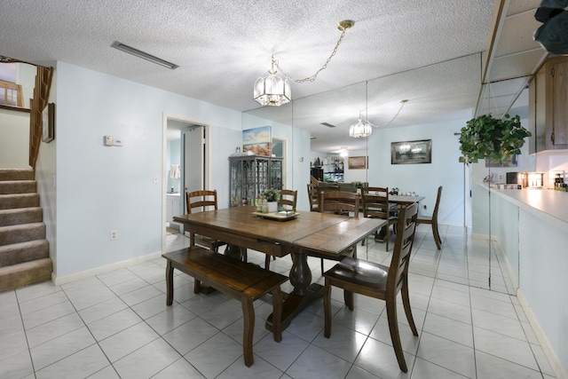 tiled dining area featuring a notable chandelier and a textured ceiling