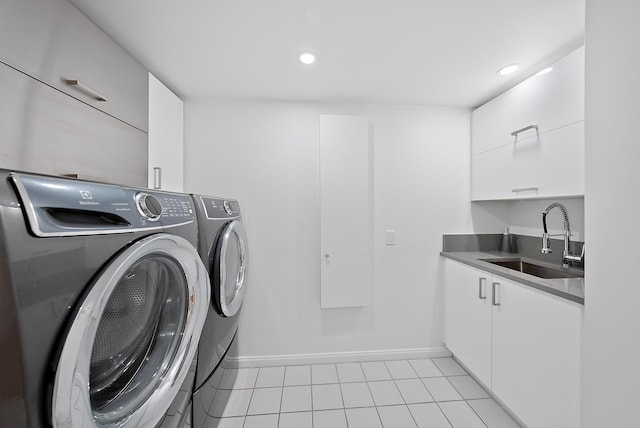 laundry room featuring cabinet space, light tile patterned floors, baseboards, washer and clothes dryer, and a sink