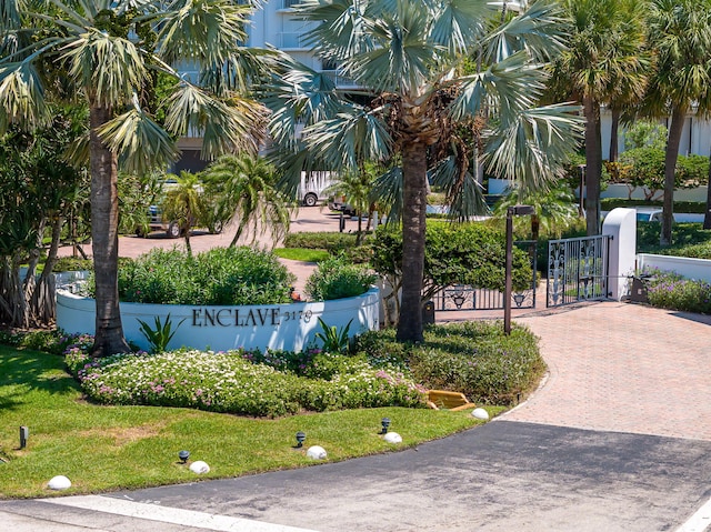 view of home's community with decorative driveway, a gate, and fence