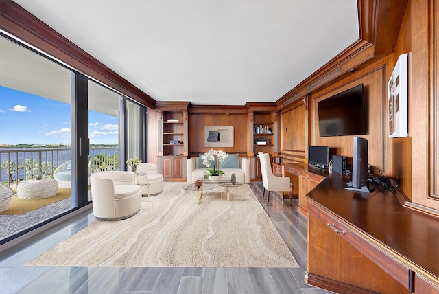 living area featuring ornamental molding, dark wood-style flooring, built in study area, and a water view