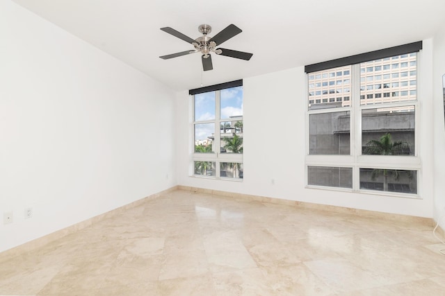 spare room with a ceiling fan and baseboards