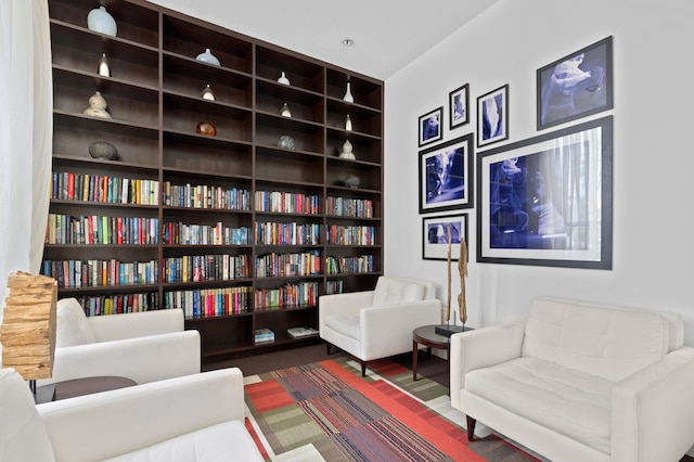 sitting room with built in shelves and dark wood finished floors