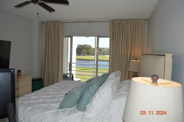 bedroom with access to exterior, a water view, a textured ceiling, and ceiling fan