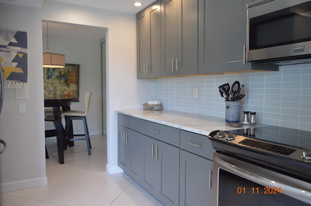 kitchen featuring appliances with stainless steel finishes, gray cabinetry, backsplash, and light tile patterned flooring