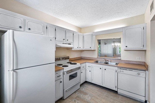 kitchen with white appliances, butcher block counters, white cabinetry, and sink