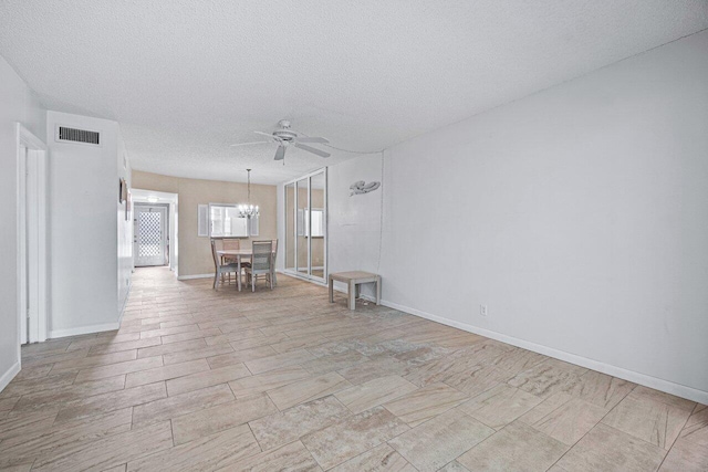 spare room with a textured ceiling and ceiling fan with notable chandelier