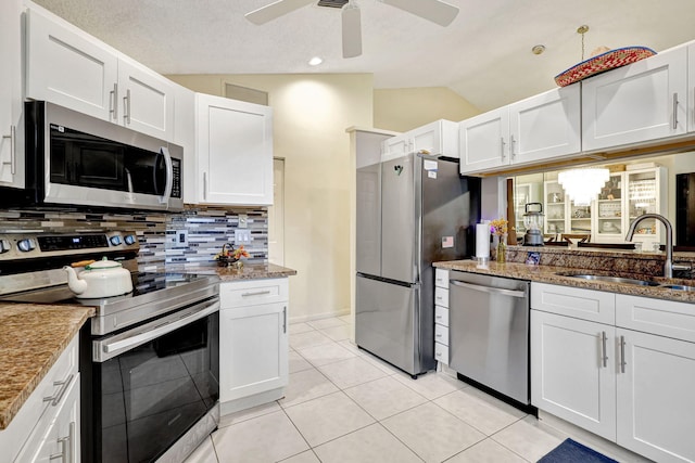 kitchen with lofted ceiling, white cabinets, sink, light tile patterned floors, and stainless steel appliances