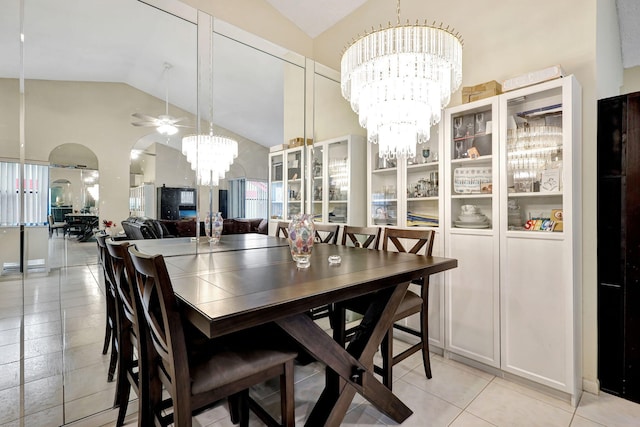 tiled dining space featuring ceiling fan with notable chandelier and vaulted ceiling