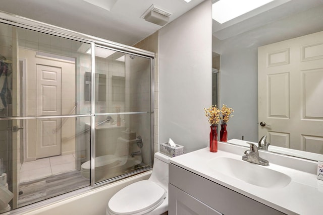 full bathroom featuring shower / bath combination with glass door, a skylight, vanity, and toilet