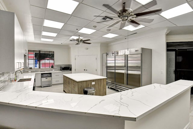 kitchen featuring kitchen peninsula, appliances with stainless steel finishes, decorative backsplash, sink, and a kitchen island