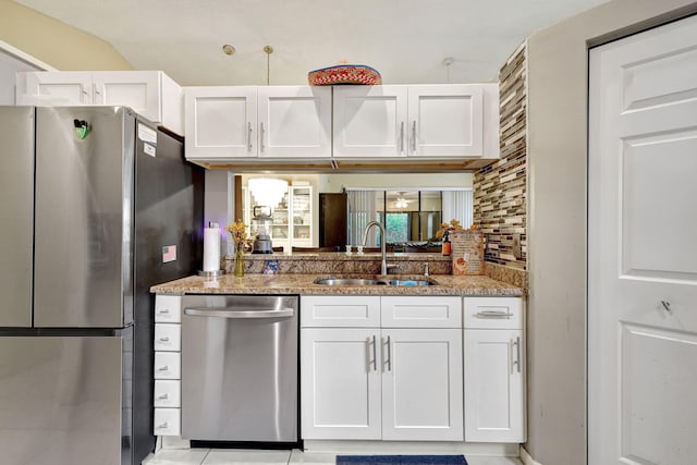 kitchen with white cabinets, stainless steel appliances, light stone countertops, and sink