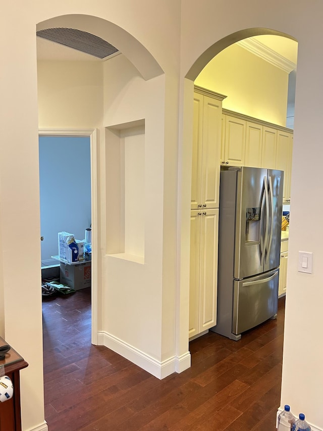 kitchen featuring cream cabinetry, stainless steel fridge, crown molding, and dark wood-type flooring