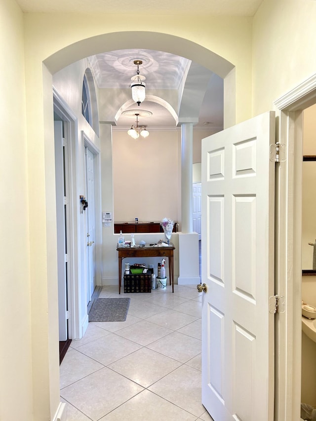 hallway featuring a chandelier, light tile patterned floors, and crown molding