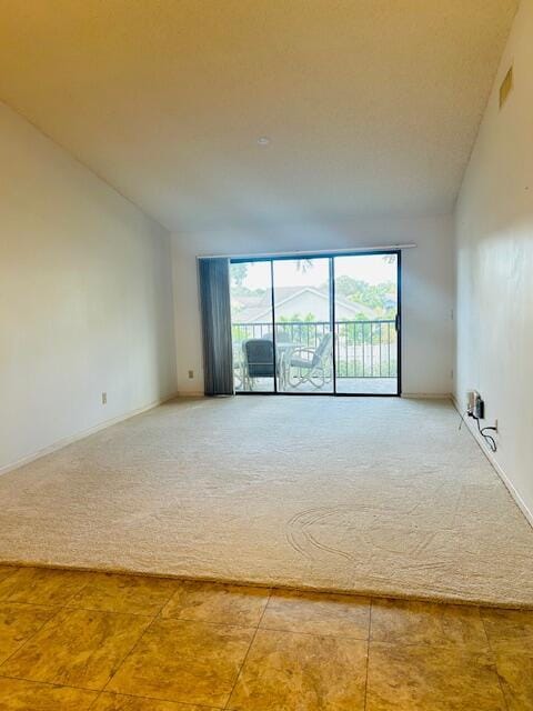 carpeted empty room with high vaulted ceiling