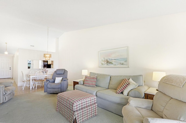 carpeted living room featuring a chandelier and high vaulted ceiling