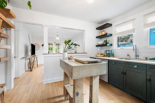 kitchen featuring backsplash, stainless steel dishwasher, sink, and light hardwood / wood-style flooring