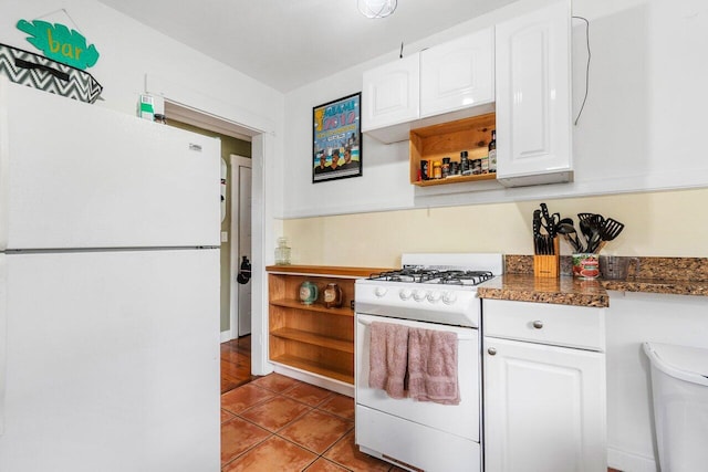 kitchen with white cabinetry, light tile patterned flooring, white appliances, and dark stone countertops