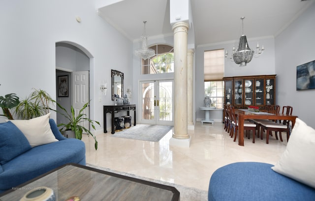 living room featuring ornamental molding, a chandelier, a towering ceiling, and french doors