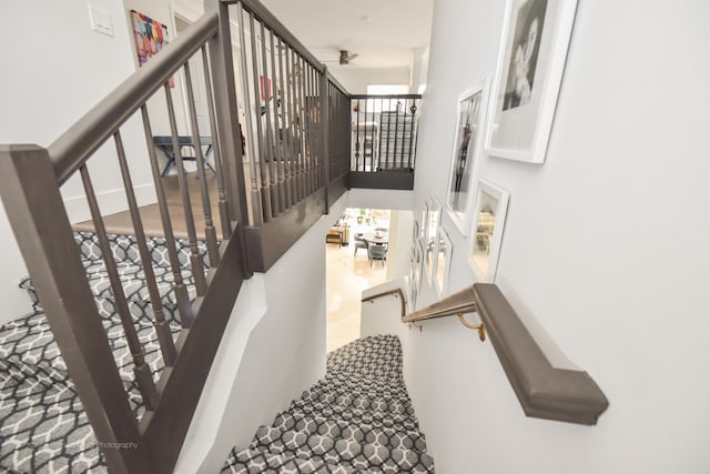 stairway featuring ceiling fan