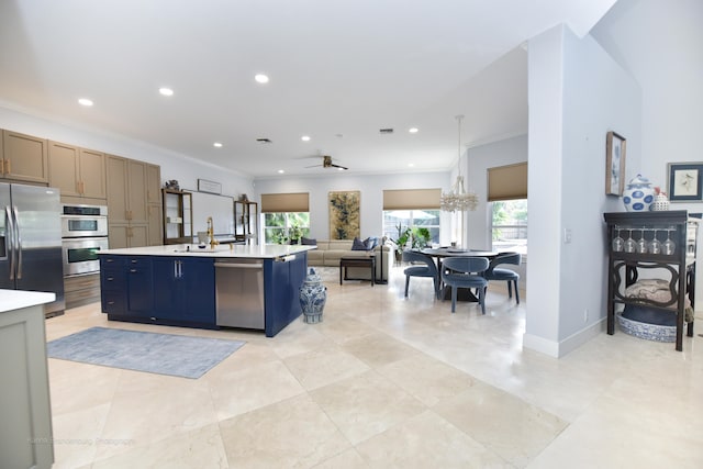 kitchen featuring appliances with stainless steel finishes, crown molding, a center island with sink, and ceiling fan