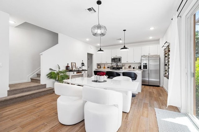 dining area featuring sink, a notable chandelier, and light hardwood / wood-style flooring