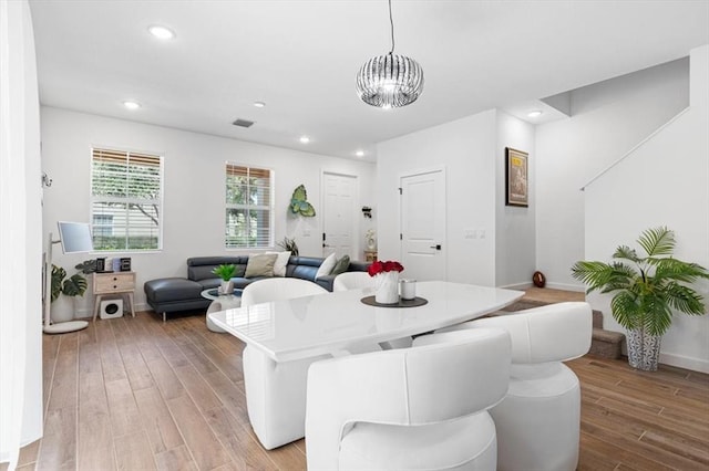 dining space with light hardwood / wood-style floors and a chandelier