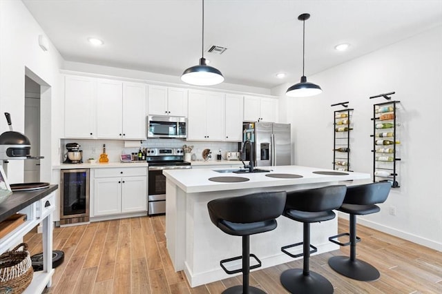 kitchen with white cabinets, appliances with stainless steel finishes, sink, and beverage cooler