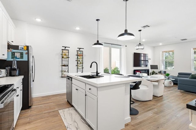 kitchen with white cabinetry, light hardwood / wood-style flooring, sink, and a center island with sink