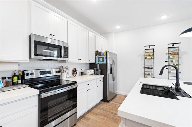 kitchen featuring appliances with stainless steel finishes, white cabinetry, sink, and light hardwood / wood-style floors